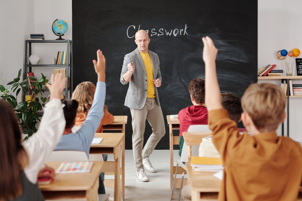 Leerkracht geeft uitleg aan leerlingen die hun hand opsteken