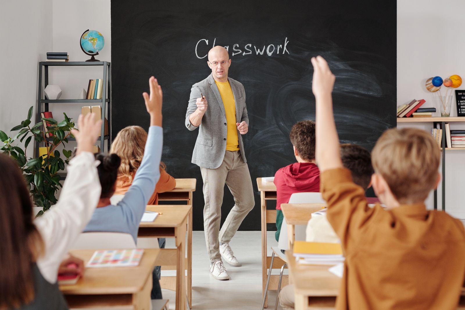 Leerkracht geeft uitleg aan leerlingen die hun hand opsteken