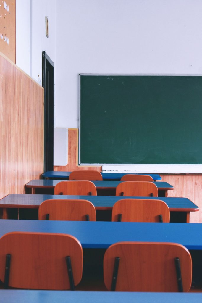 Leeg klaslokaal met houten schoolbanken en een groen bord